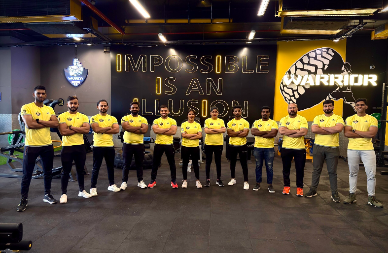 "Professional trainers at Warrior Gym posing together inside a modern fitness center, showcasing the experienced coaching team dedicated to strength training, weight loss, and overall fitness."